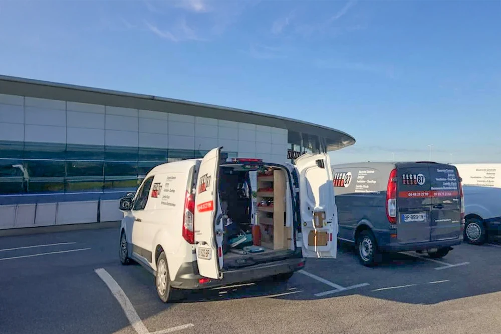 Agent de sécurité en uniforme noir avec inscription "SECURITY" surveillant un mur d'écrans de vidéosurveillance dans une salle de contrôle