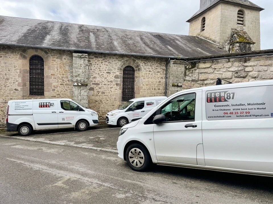 Mécanicien automobile en combinaison bleue remplaçant une batterie de voiture dans un garage professionnel
