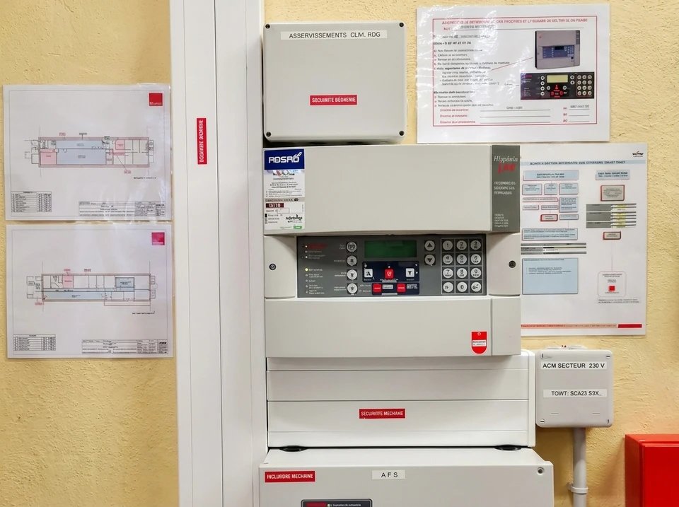 Scène industrielle avec technicien en équipements de protection travaillant sur installation de tuyauterie rouge et systèmes de sécurité incendie